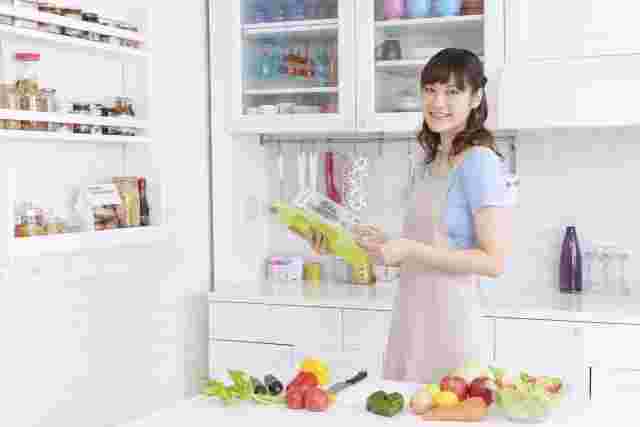 キッチンで微笑みながら本を開く女性