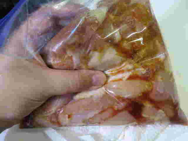 袋に入れた鶏肉を左手で揉み込んでいる画像