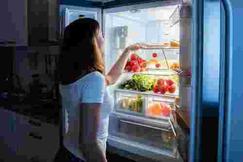 冷蔵庫を開け、食品を取り出そうとする女性