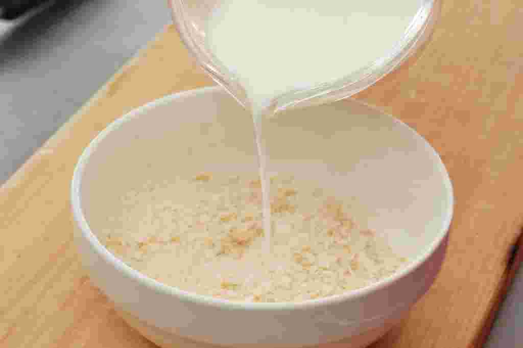 器に入ったパン粉に牛乳を加えている様子
