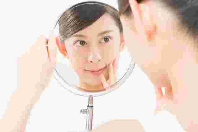 鏡で肌の調子を確認する女性