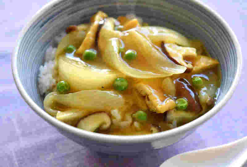 お洒落な丸い丼にくし切り玉ねぎ、グリーンピースや野菜にカレールーがかかっている