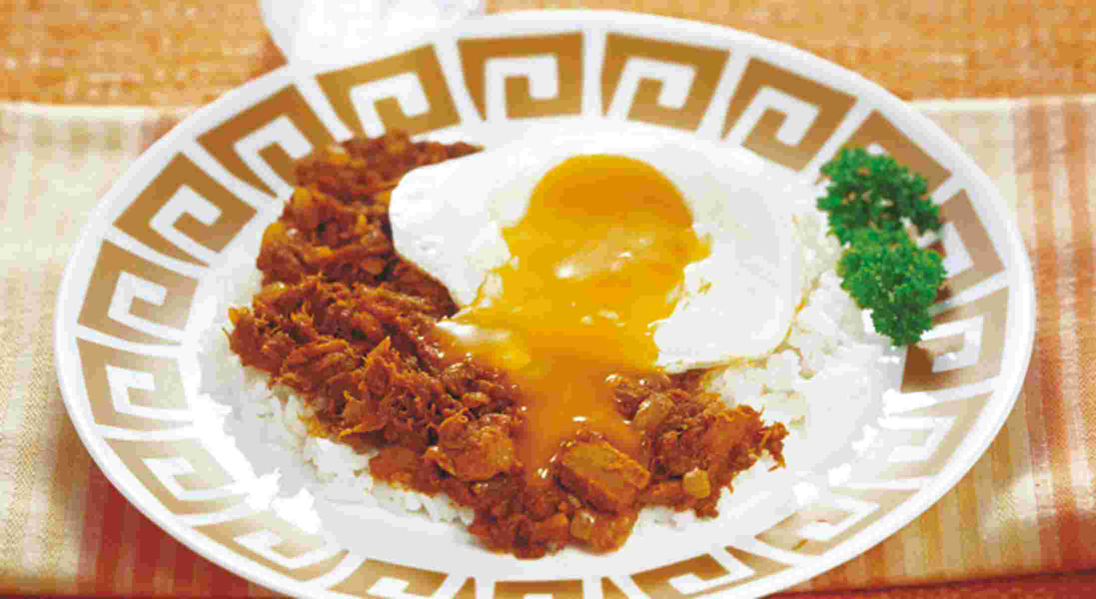 お洒落な模様の入った丸い皿にご飯、カレー、パセリ、黄みがとろけた目玉焼きがのせてある