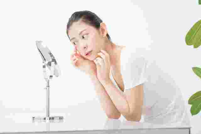 鏡で肌の調子を確認する女性