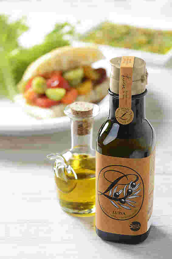 料理の前に透明なボトルとグリーンにオレンジ色のシールがついたオリーブオイル