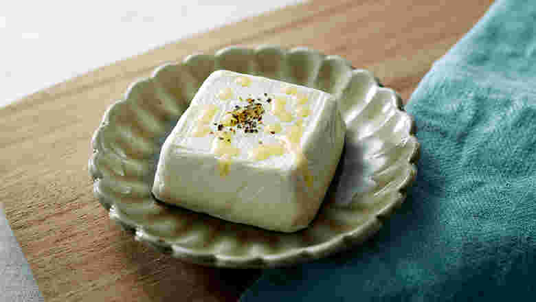 グリーンの小さな器に入った豆腐にかかったオリーブオイル