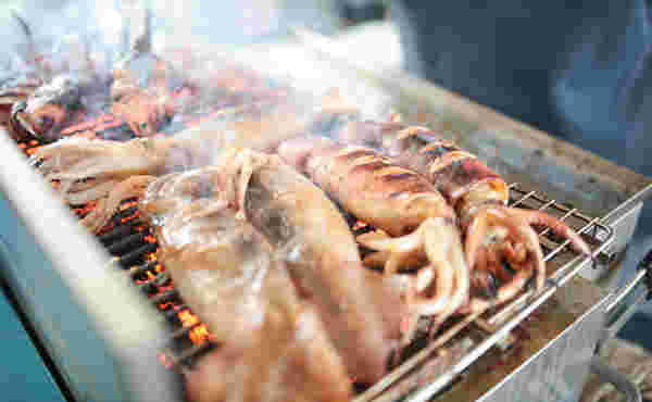 網の上で焼かれたたくさんのイカ