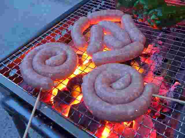炭火で焼かれたぐるぐるソーセージとウインナーとピーマン
