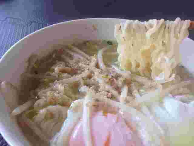 もやしと卵が乗ったラーメンを箸でひとつまみ