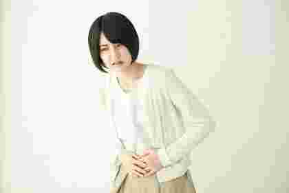 お腹の不調を感じてお腹を押さえている女性