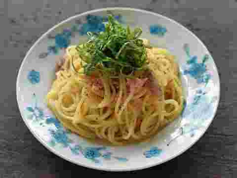 お洒落な柄の入った丸い皿に調理されたパスタと刻まれた青じそが上に盛られている