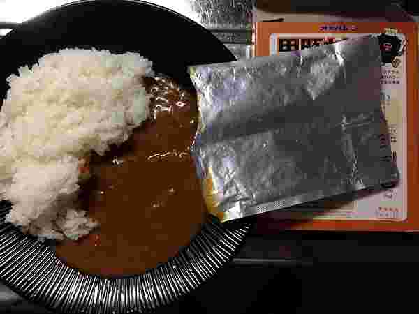お皿にレトルトカレーを盛り付けしている様子