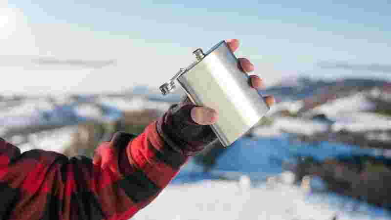 冬の雪の中で左手に持ったスキットル