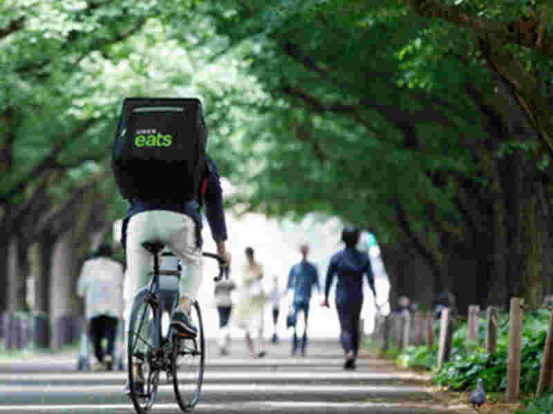 木々の間を自転車で走るウーバーイーツの配達人