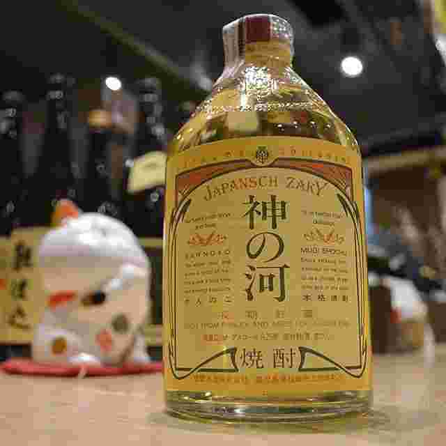 テーブルの上に神の河という麦焼酎の瓶を置いている様子