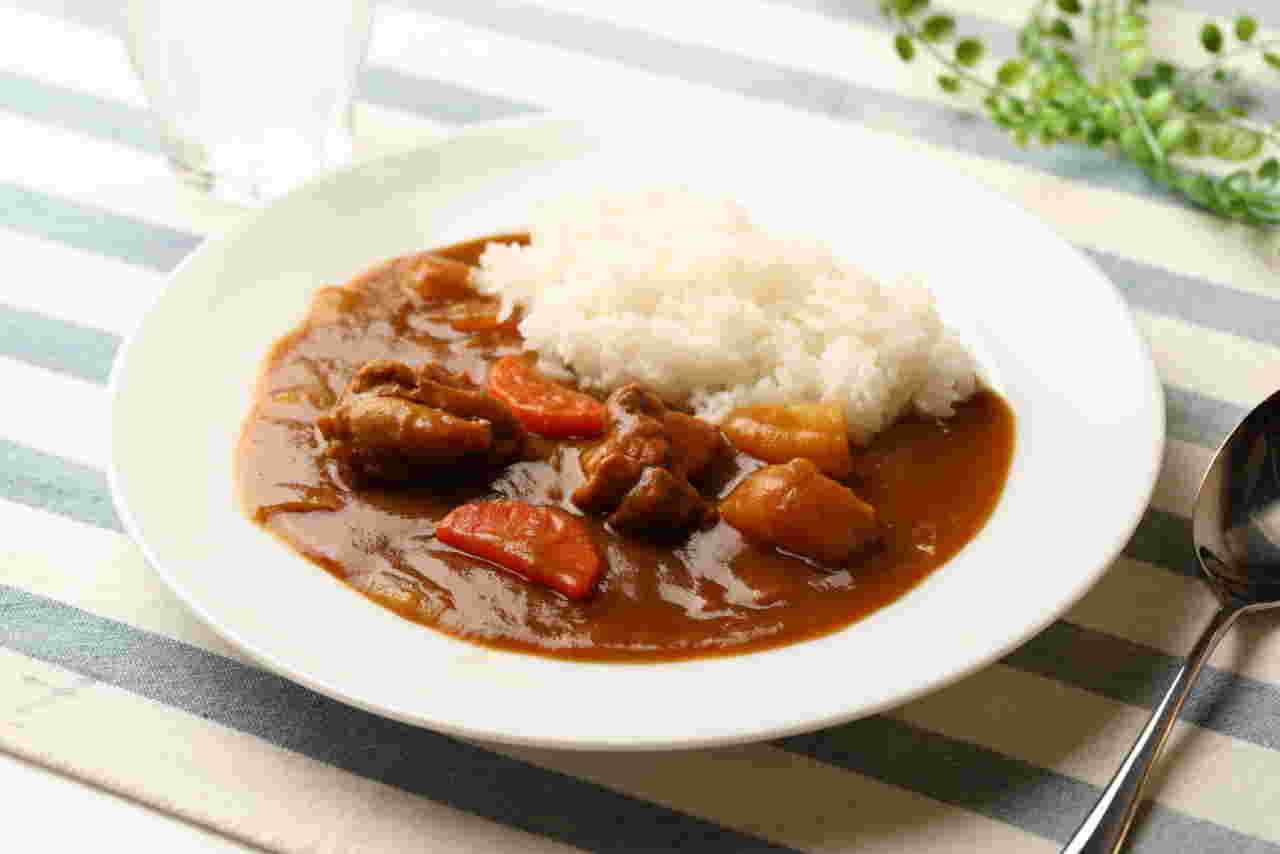 スプーンと白いお皿にカレーライスが盛られている様子