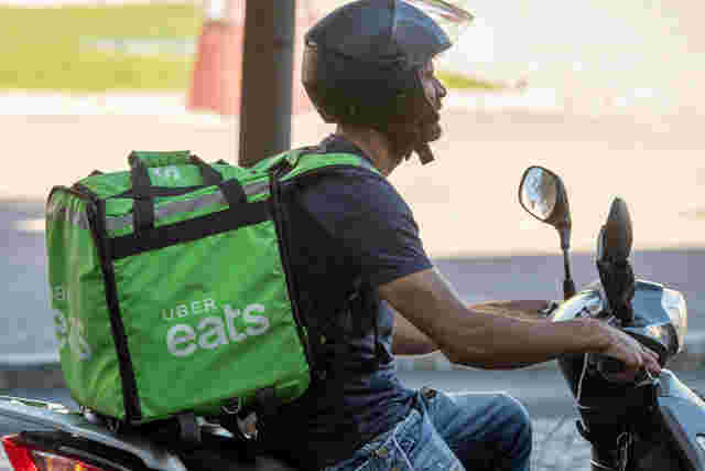 バイクに乗って配達するUberEats配達員
