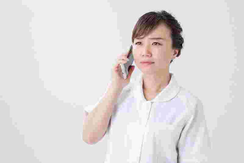 困った顔で電話する女性