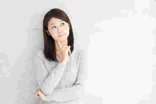 人差し指を顎に当てて考え込む女性