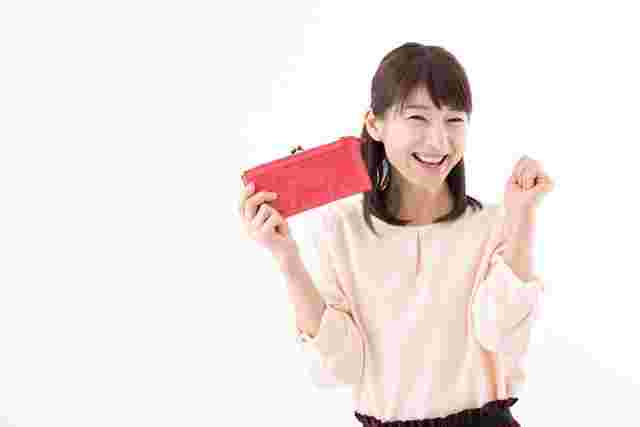 財布を手に持ちガッツポーズをとる笑顔の女性
