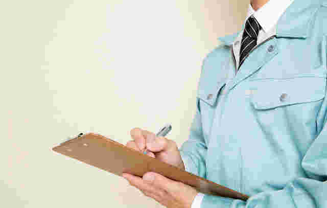 作業服の男性が何か書いている様子