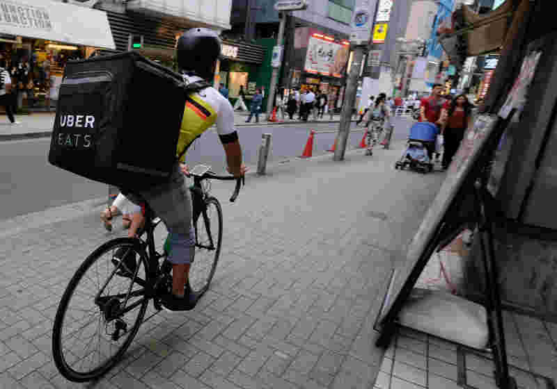 ウーバーイーツのリュックを背負って自転車をこいでいる人