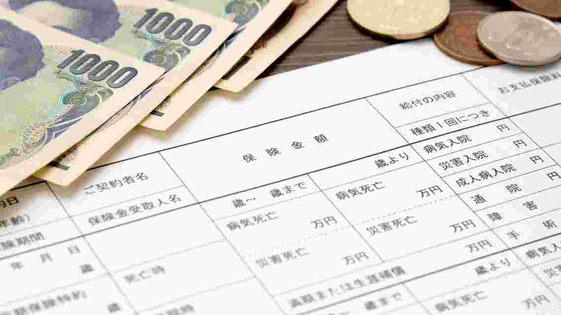 保険内容が書かれた書類と紙幣と小銭が並べられている様子