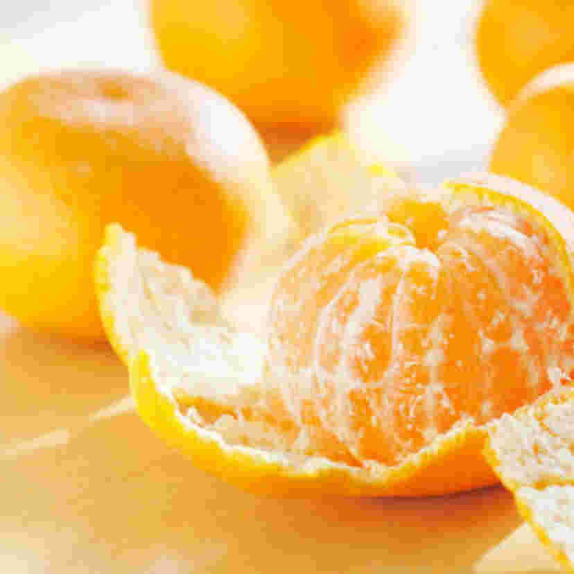 皮付きのみかんと途中まで皮がむかれたみかんが並んでいる様子