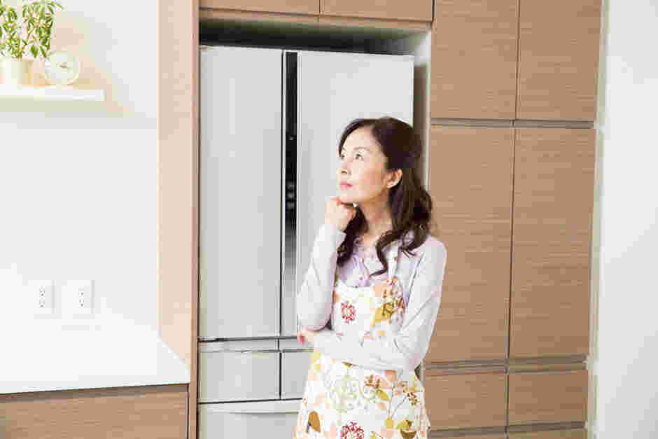冷蔵庫を背景に悩む女性