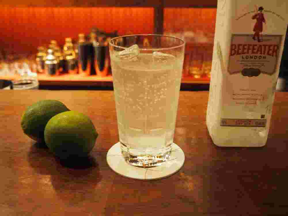 白いお酒の瓶と背の高いグラス入ったお酒とライムが並んでいる様子