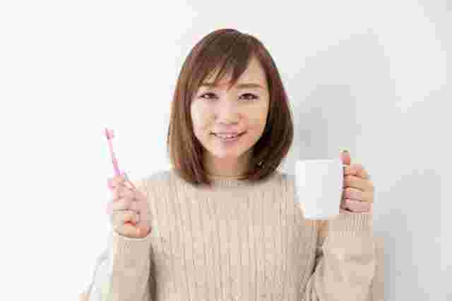 コップと歯ブラシを持った女性