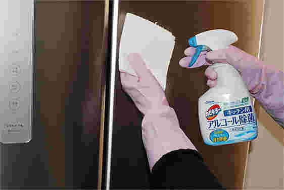 アルコール除菌スプレーで冷蔵庫を掃除している
