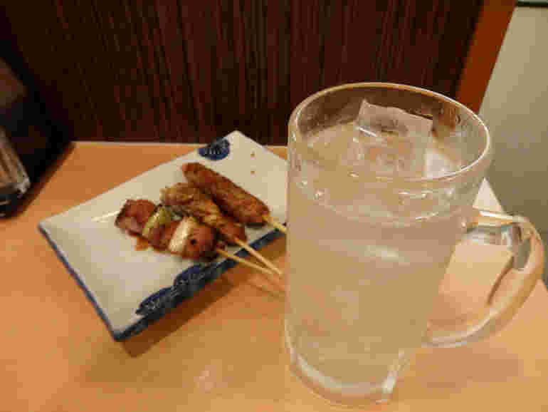 ジョッキに入ったレモンハイと居酒屋メニューの焼き鳥の様子