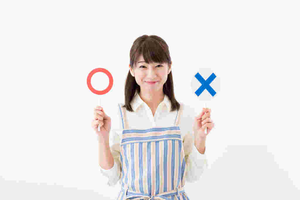〇と×のスティックを手に持ち微笑む女性