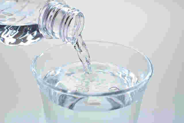 ペットボトルの水をグラスに注ぐ