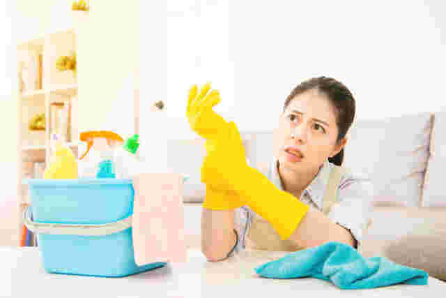 漂白剤などをバケツに入れ、掃除用手袋はめながら不安げな表情を浮かべる女性