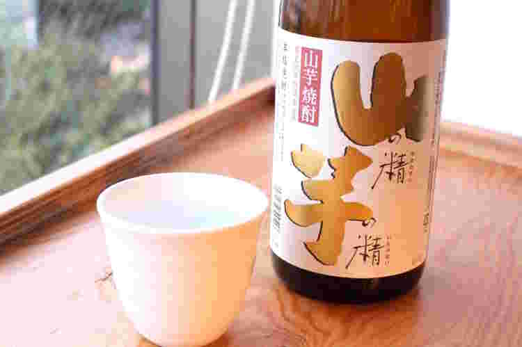 山芋焼酎「山の精芋の精」のボトルと焼酎が注がれたカップ