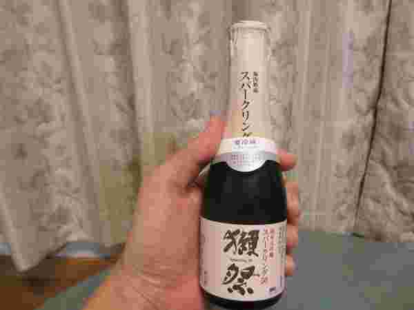 獺祭(だっさい)というお酒の瓶を手に持っている様子