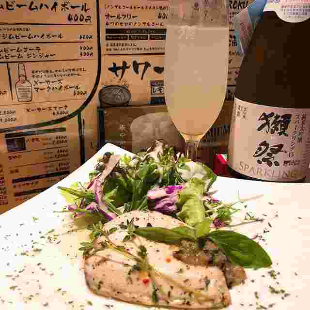 白いお皿にチキンソテーがあって、その奥に獺祭というお酒が置かれている様子