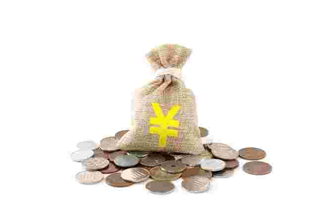 黄色の円マークがついた袋の下に、硬貨がたくさん置かれている様子