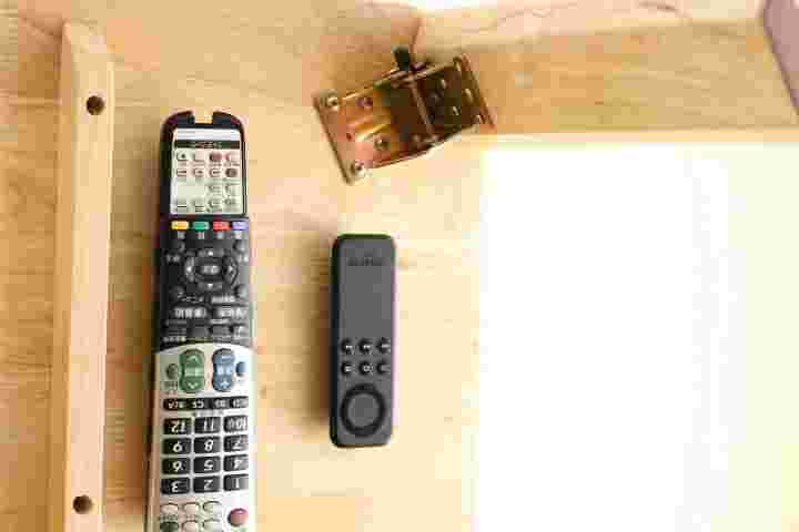 テレビのリモコンをテーブルの裏に収納している様子