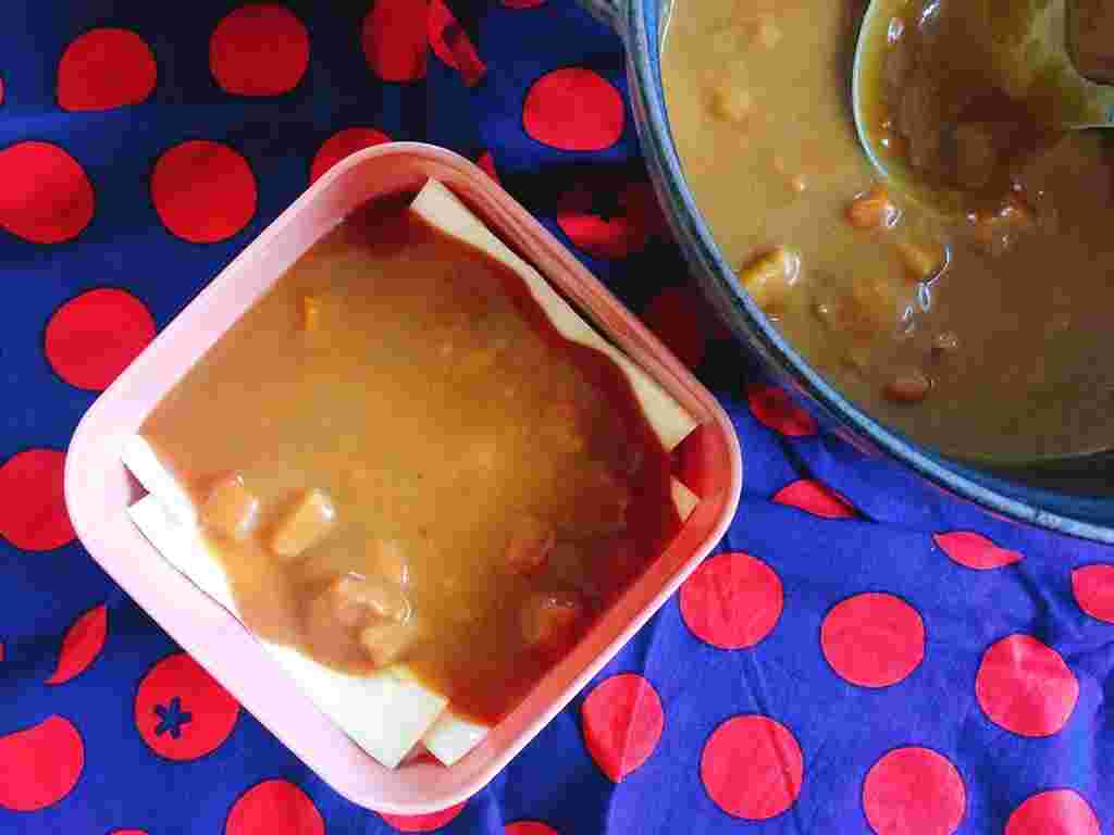 タッパーにチーズとカレーを入れている様子
