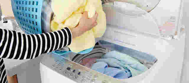 衣類などを洗濯機に入れている様子。