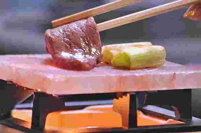岩塩プレートに肉やねぎをのせる