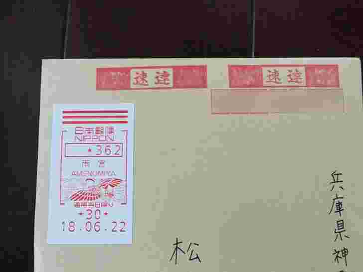 茶封筒に速達印鑑と切手が貼られている様子
