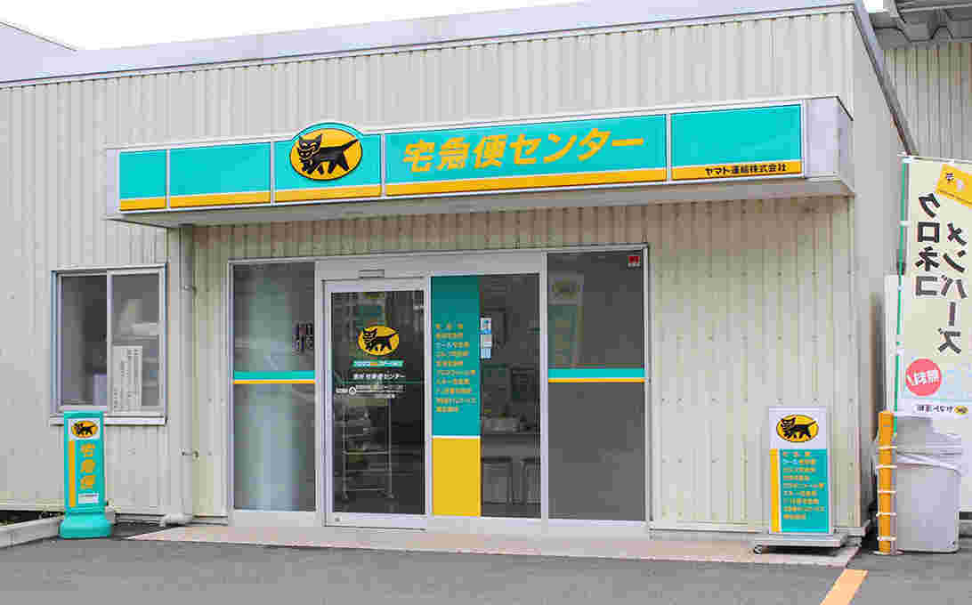 緑の看板に黄色の文字で宅急便センターと書かれた、ヤマト運輸の外観の様子