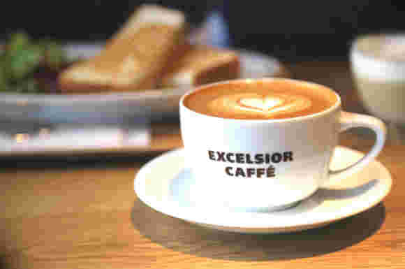 木製のテーブルに白いカップ&ソーサーに入ったエクセルシオールカフェのコーヒー