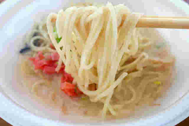 豚骨ラーメンの麵を箸で持ち上げている様子