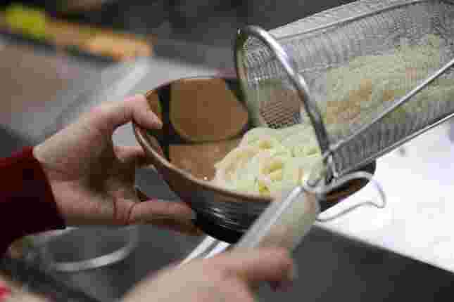 湯切りしたうどんを丼に盛り付ける様子
