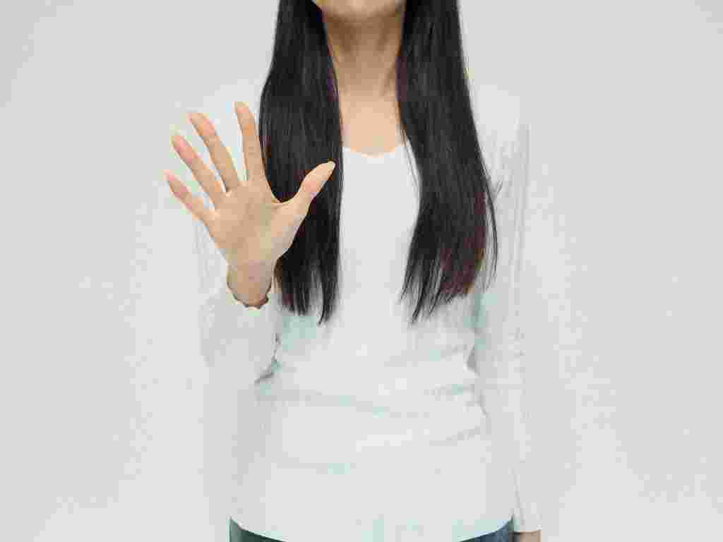 片手の手のひらを相手に向ける女性